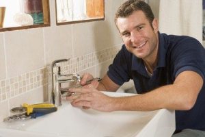 Male plumber fixing a sink with tools.